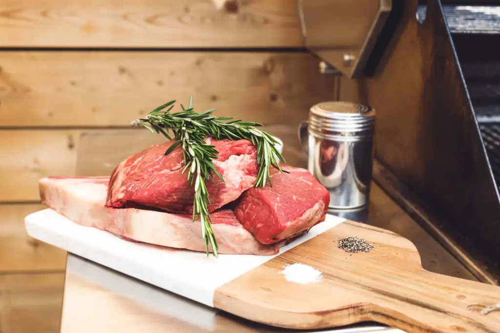 Pièces de bœuf crues et romarin sur une planche