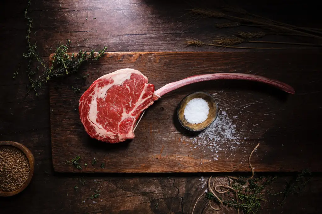 Côte de bœuf crue sur une planche en bois, avec gros sel